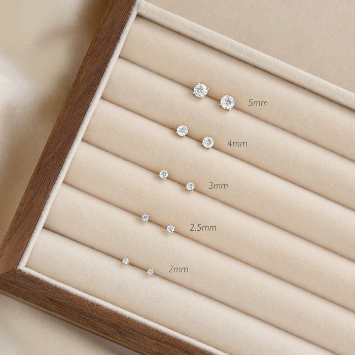 Elegant White Gold jewelry display showing a set of diamond earrings, arranged by size from 2mm to 5mm, on a beige velvet holder with wooden frame.