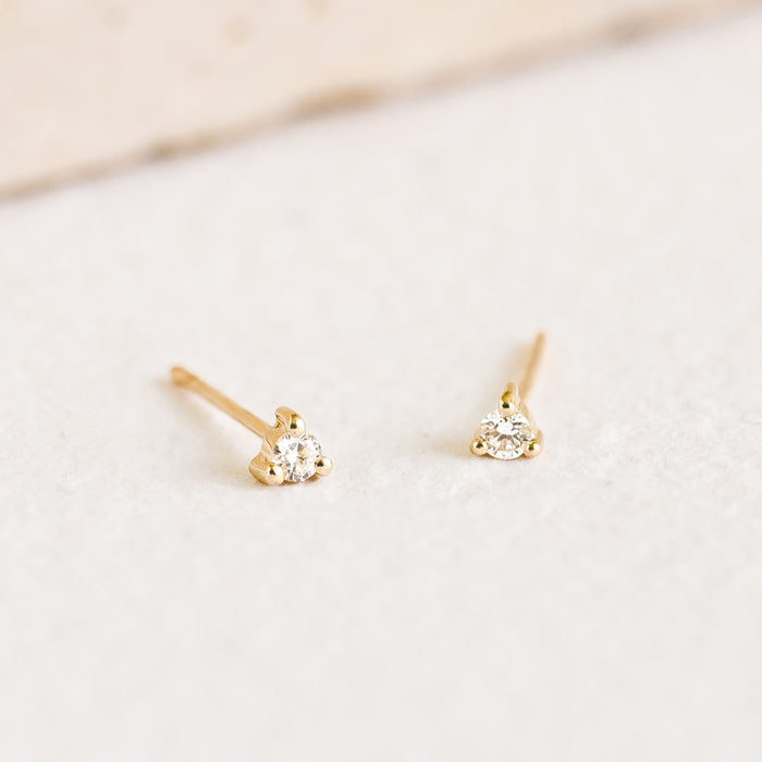 Close-up of 14k Yellow Gold Diamond Stud Earrings 2mm - Aria with lab grown diamonds on a soft white surface