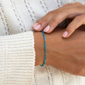 Close-up of a woman wearing a dainty Apatite Bracelet with gold vermeil beads styled with a white knit sweater