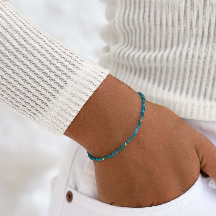 Close-up of a wrist wearing a delicate Apatite Bracelet with gold vermeil bead accents and a white ribbed sweater sleeve