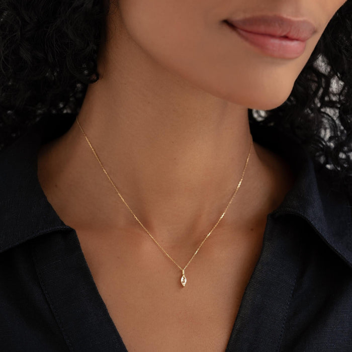 Close-up of woman wearing April Birthstone Pendant 14k Gold - White Topaz with black collared shirt on neutral background