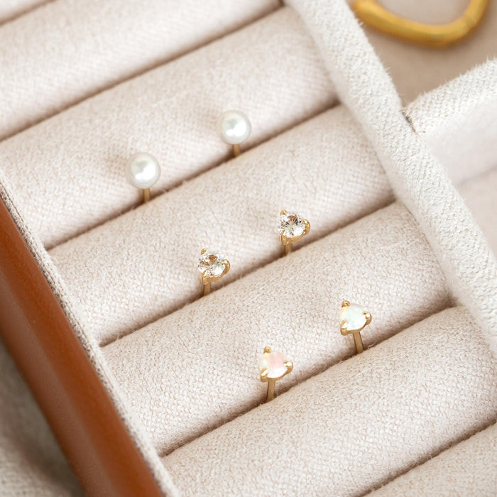 April Birthstone Stud Earrings 14k Gold - White Sapphire displayed in a beige jewelry organizer with gold settings