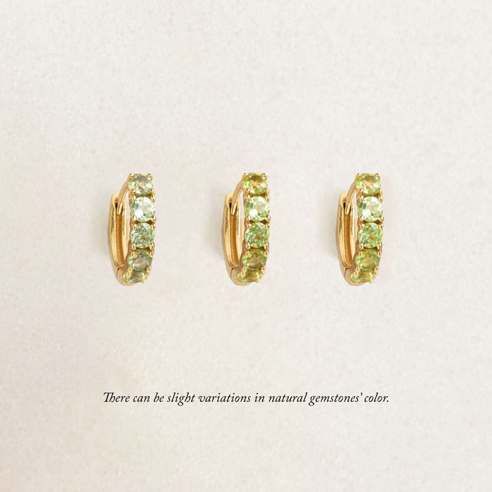 Three Gold Eternity huggie earrings featuring rows of small gemstones, displayed against a soft cream background.