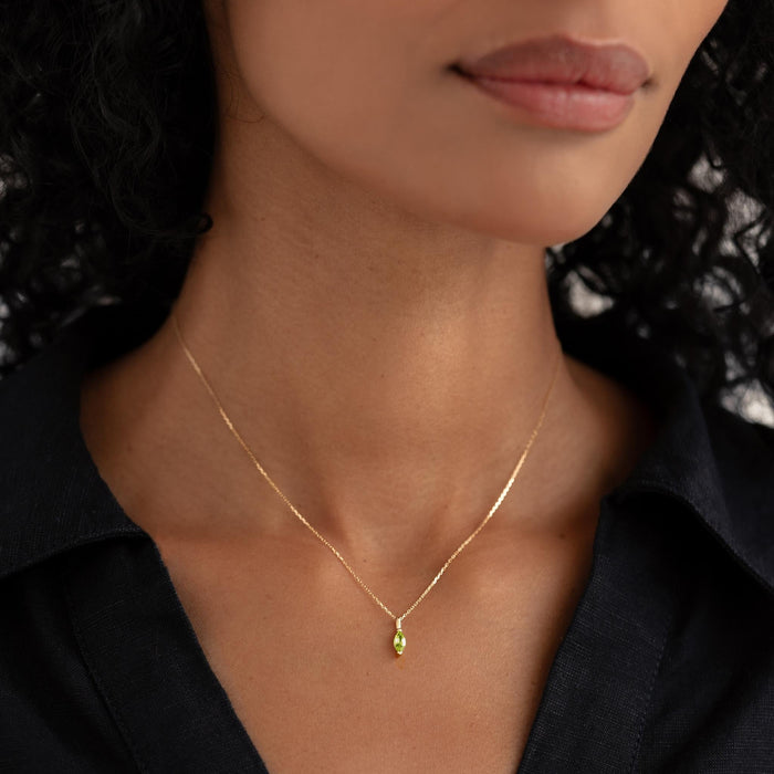 Close-up of woman wearing August Birthstone Pendant 14k Gold - Olivine on a delicate gold chain with black top