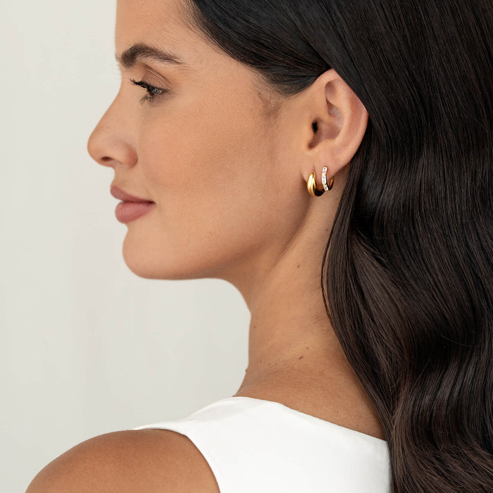 Side profile of a woman wearing two Gold Vermeil earrings—one plain and one set with baguette-cut gemstone—styled as an ear stack, shown against a soft neutral background with dark hair.