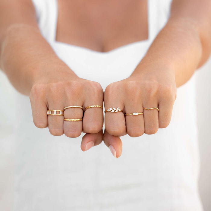 Gold stacking rings on model with textured bands and gemstone rings in gold vermeil