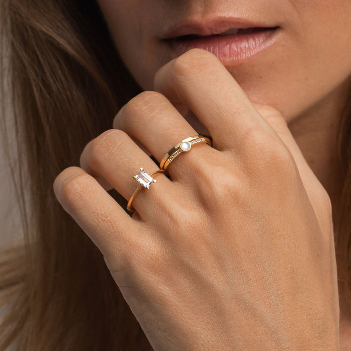 White topaz gemstone ring in baguette cut stacked on model’s hand with gold bands