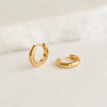 Chunky Huggie Hoop Earrings - Dione in gold vermeil with a smooth, polished finish on a neutral background