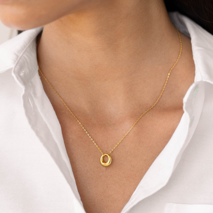 Close-up of a woman wearing the Circle Pendant Necklace - Lilou in gold vermeil with a white collared shirt background