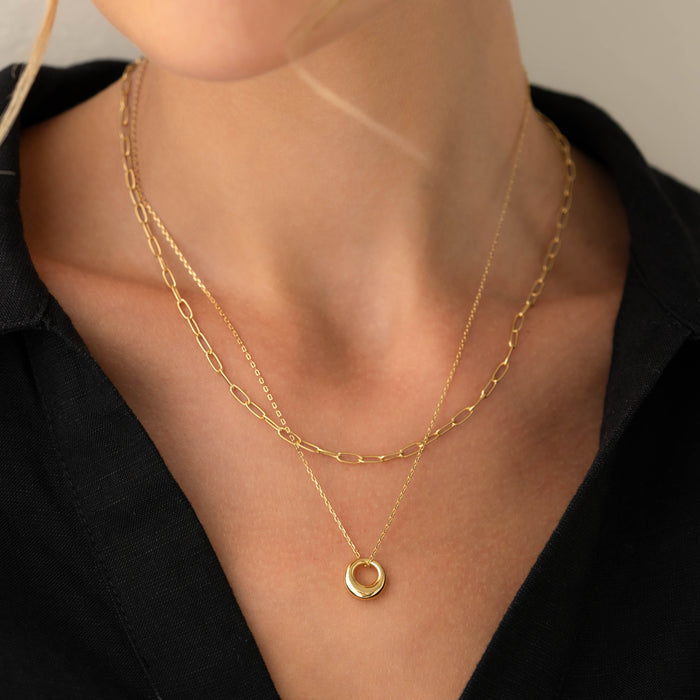 Close-up of layered gold chains featuring the Circle Pendant Necklace - Lilou worn with a black top