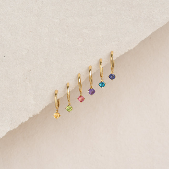 December Birthstone Drop Huggie Earrings - Cordierite with gold vermeil and multiple colored gemstones on beige background