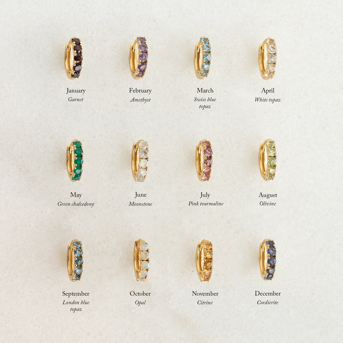 Set of twelve gold vermeil birthstone huggie earrings featuring December Birthstone Huggie Earrings - Cordierite among others on a neutral background