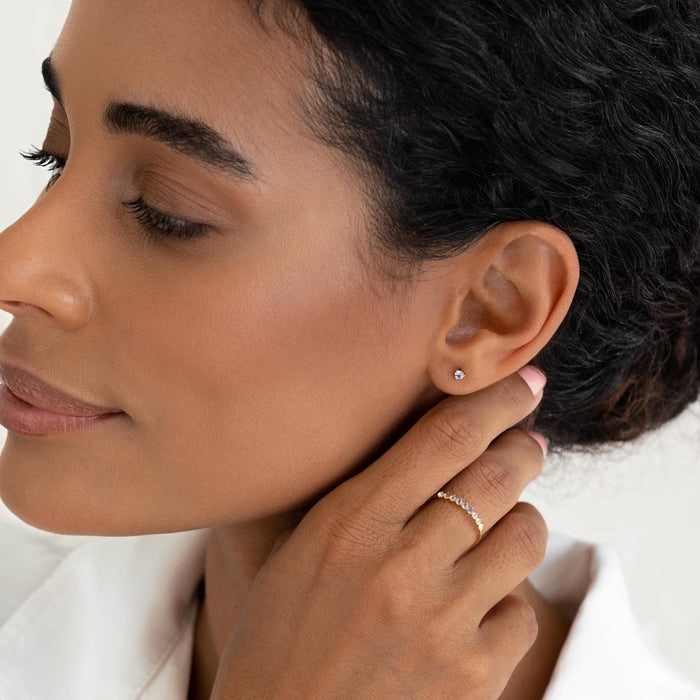 Close-up of woman wearing December Birthstone Stud Earrings 14k Gold - Tanzanite with a white blouse on a white background