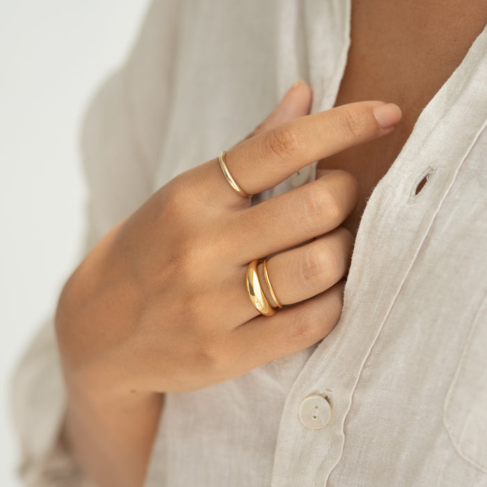 Close-up of a hand wearing Dome Ring - Arielle with a tapered gold vermeil band on a neutral fabric background