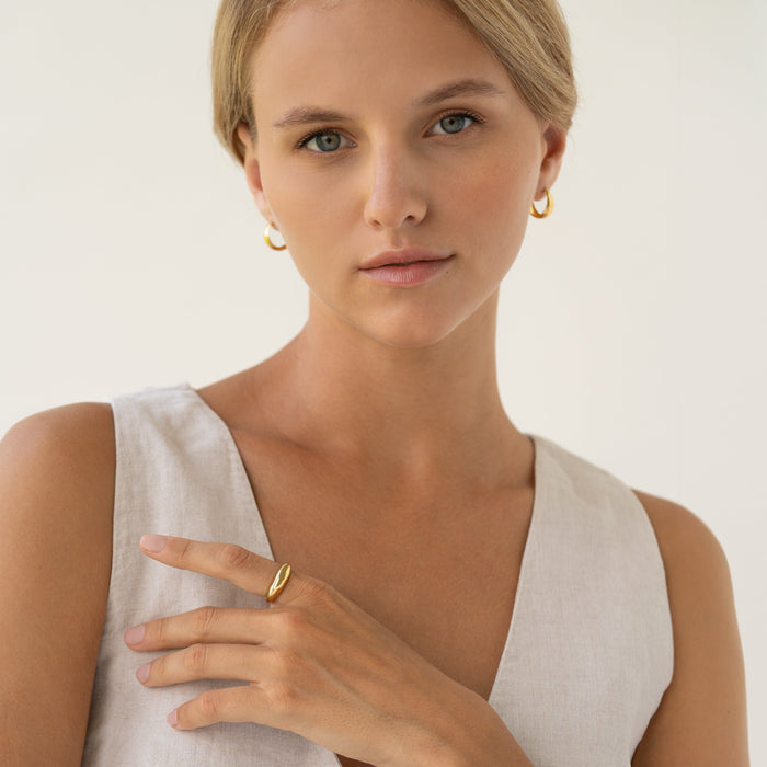 Close-up of a woman wearing the Dome Ring - Arielle with a tapered gold vermeil design and neutral linen top