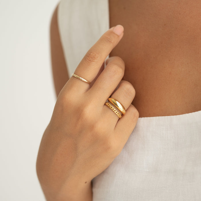 Close-up of hand wearing Dome Ring - Arielle with a tapered puffy gold vermeil design and two gold stacking rings