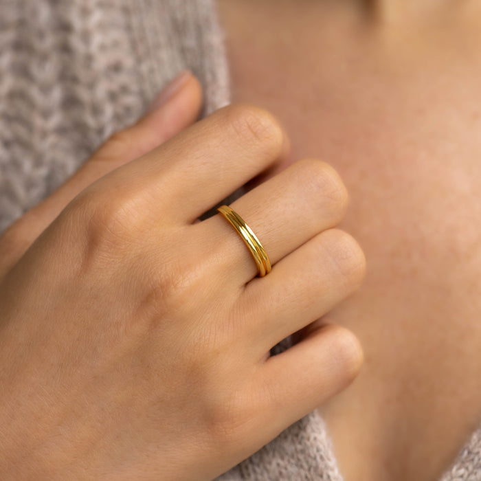 Close-up of a hand wearing the gold vermeil Double Stacking Ring - Idalia with a soft ribbed design on a neutral background