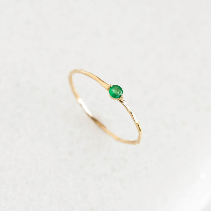 Emerald Ring 14k Gold - Penelope with an organic 14k gold band and small round emerald center stone on neutral background