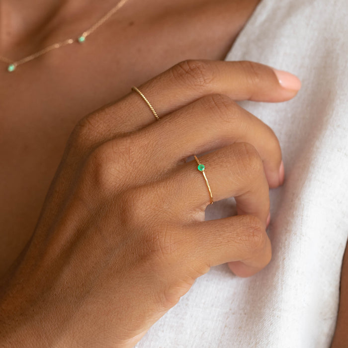 Close-up of hand wearing Emerald Ring 14k Gold - Penelope with a delicate gold band and small round emerald stone