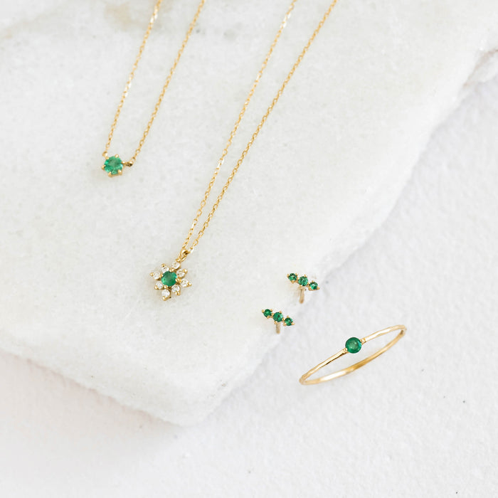 Emerald Ring 14k Gold - Penelope with delicate gold chain necklaces and emerald stud earrings on a white background