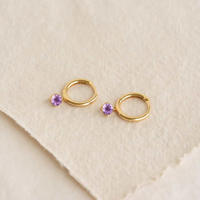 February Birthstone Drop Huggie Earrings - Amethyst with gold vermeil setting on textured beige paper background