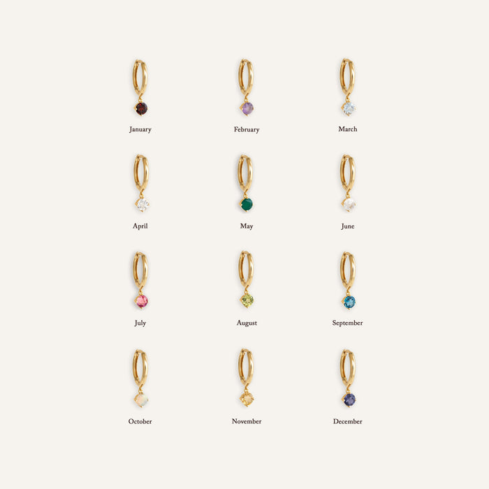 Display of twelve gold vermeil huggie earrings featuring monthly birthstones including February Birthstone Drop Huggie Earrings - Amethyst