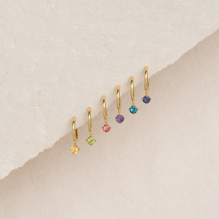 Close-up of February Birthstone Drop Huggie Earrings - Amethyst and other colorful gemstones on a beige background