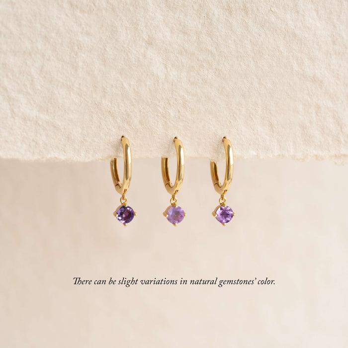 Close-up of February Birthstone Drop Huggie Earrings - Amethyst on a beige background noting there can be slight variations in natural gemstones' color