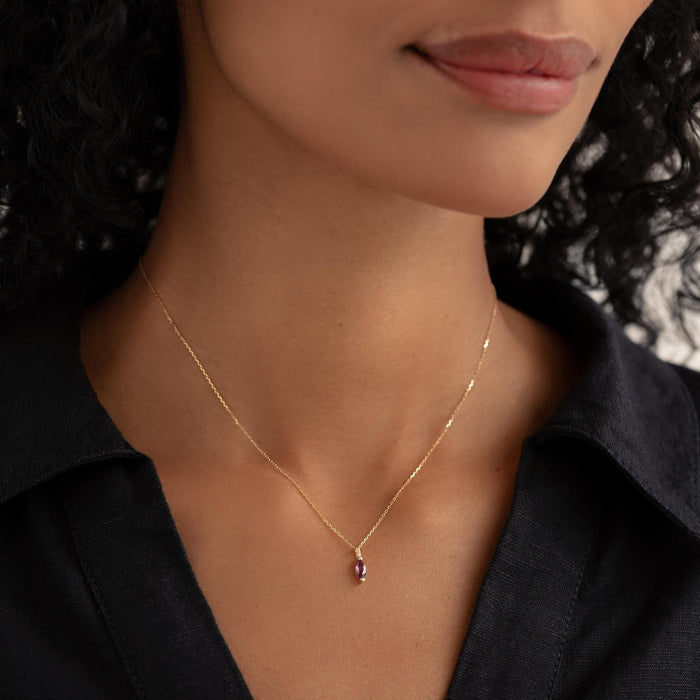 Close-up of a woman wearing the February Birthstone Pendant 14k Gold - Amethyst with a black collared shirt