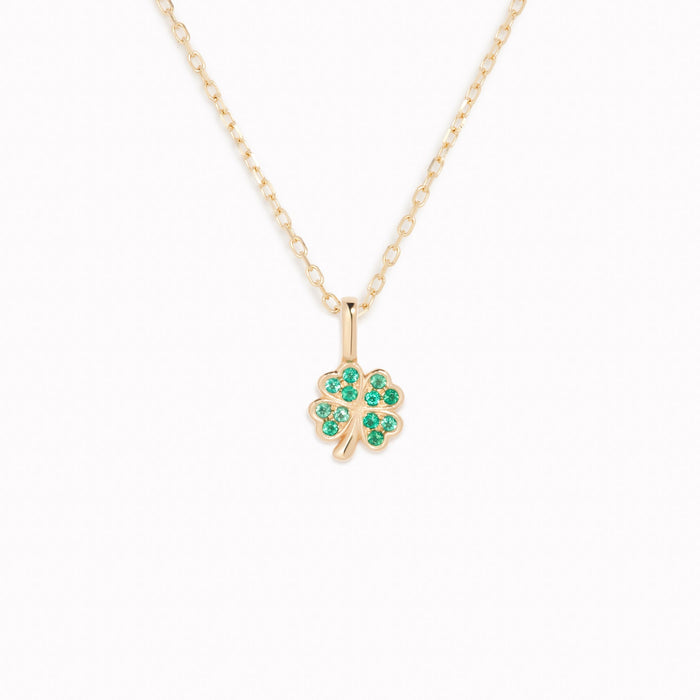 Four Leaf Clover Charm 14k Gold necklace with emerald gemstones on a delicate yellow gold chain on white background