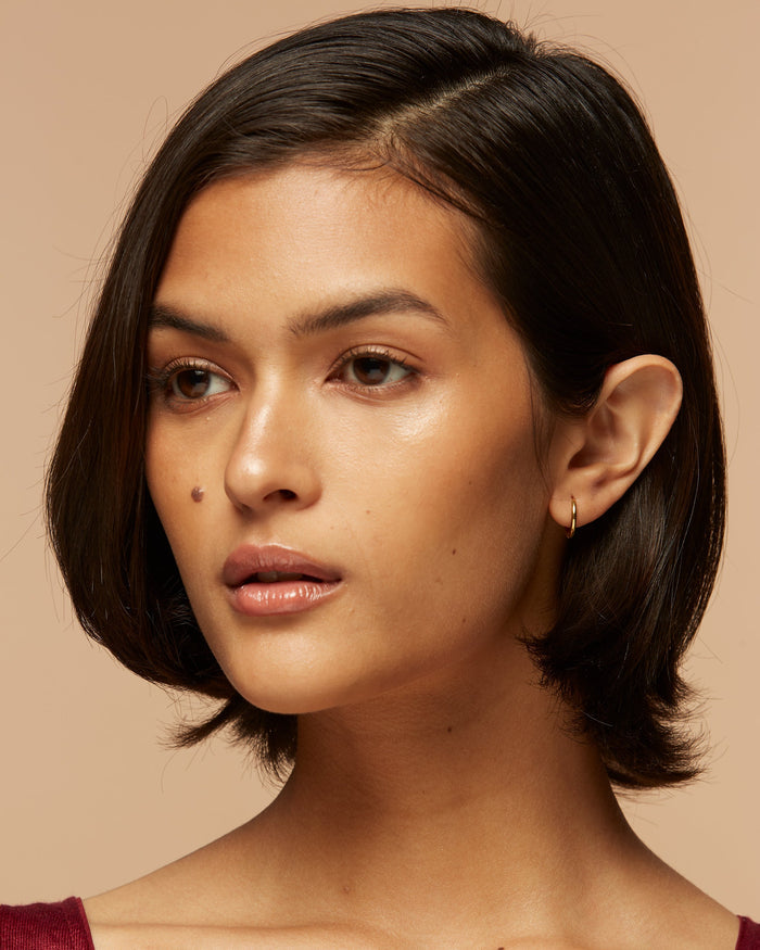 Small gold hoop earrings on model