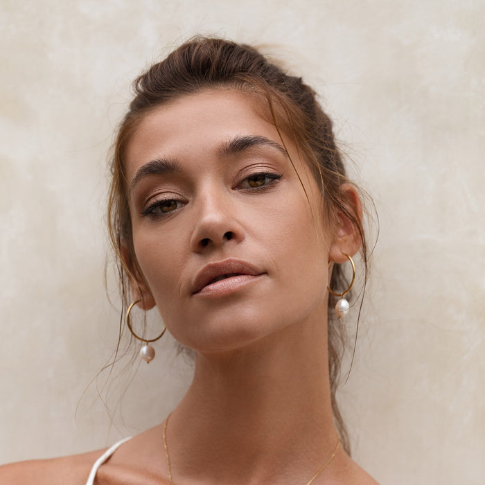 Freshwater pearl drop earrings in gold vermeil on model