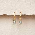 Huggie Earrings with Baguette Charms Sky Blue Topaz - Amelia gold vermeil hoops with rectangular sky blue topaz charms on neutral background