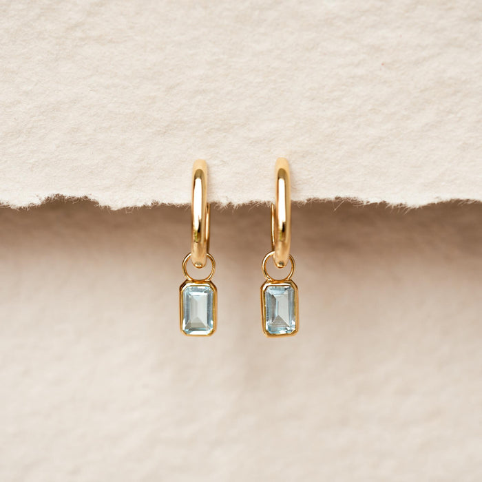 Huggie Earrings with Baguette Charms Sky Blue Topaz - Amelia gold vermeil hoops with rectangular sky blue topaz charms on neutral background