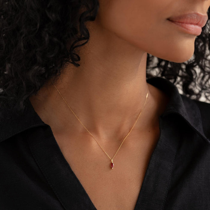 Close-up of a woman wearing the January Birthstone Pendant 14k Gold - Garnet with a black collared shirt