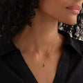 Close-up of a woman wearing the January Birthstone Pendant 14k Gold - Garnet with a black collared shirt