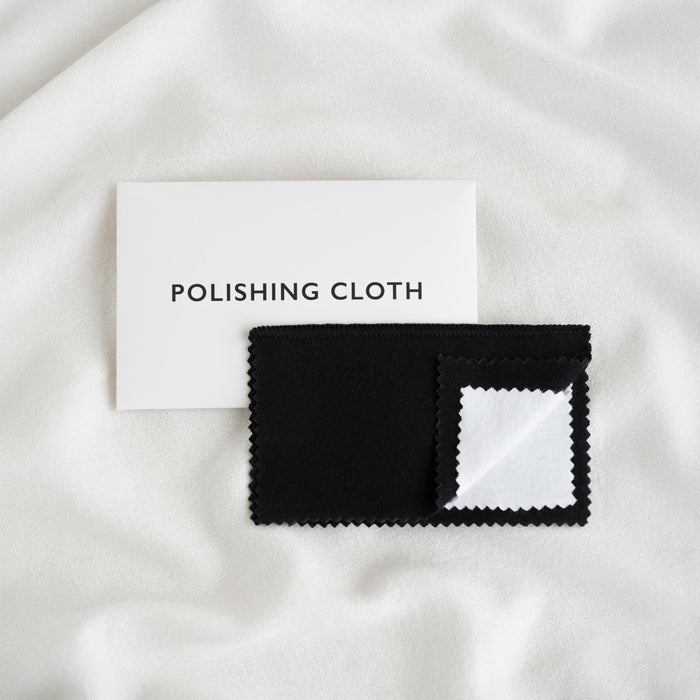 Jewelry Polishing Cloth with black and white layers displayed on soft white fabric background