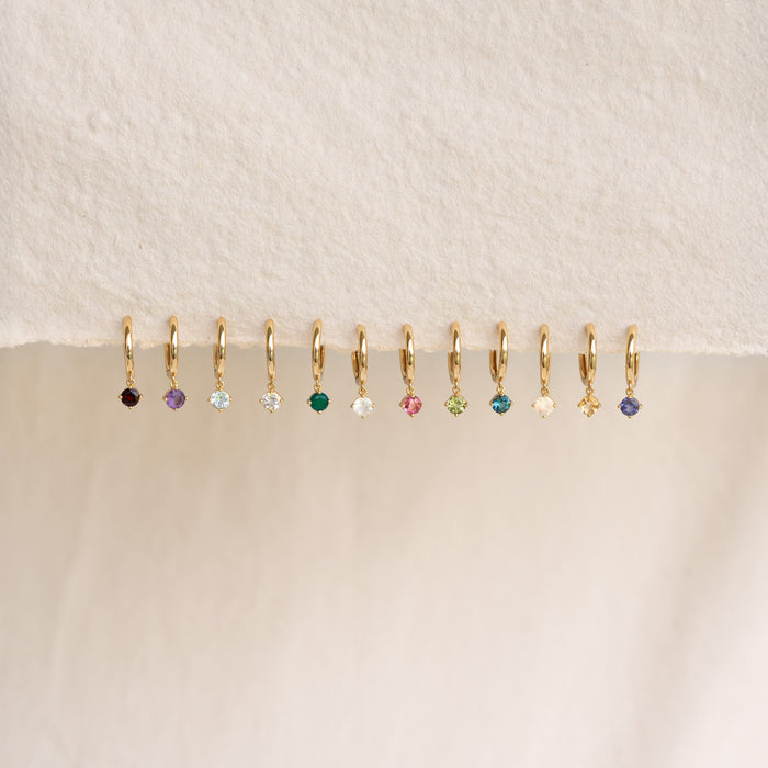Row of delicate gold drop huggie earrings featuring various gemstones including June Birthstone Drop Huggie Earrings Moonstone