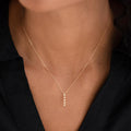 Close-up of woman wearing Diamond Drop Pendant 14k Gold on a delicate yellow gold chain with a black top