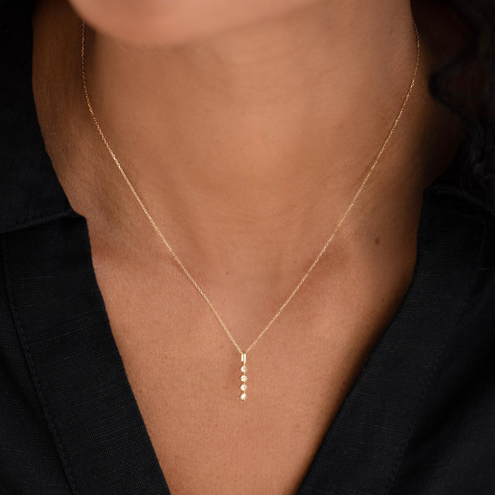 Close-up of woman wearing Diamond Drop Pendant 14k Gold on a delicate yellow gold chain with a black top