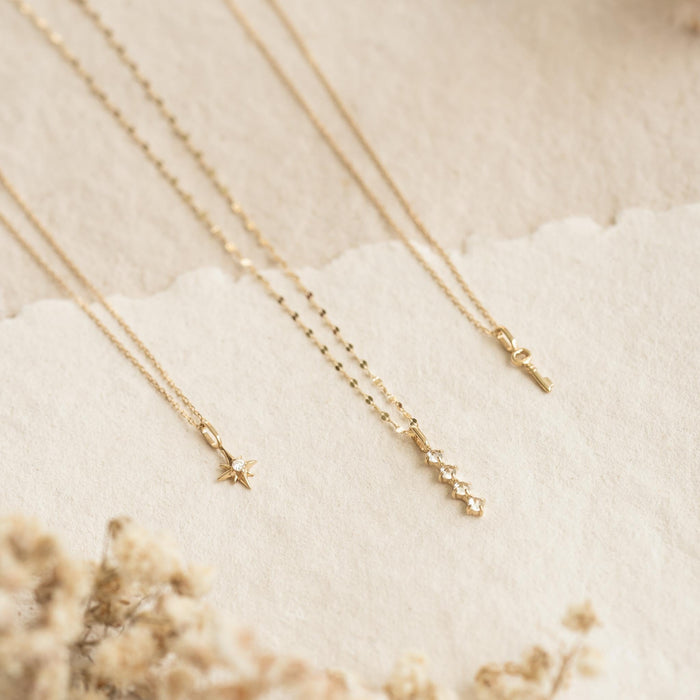 Diamond Drop Pendant 14k Gold with four lab grown diamonds on a delicate yellow gold chain displayed on soft beige background