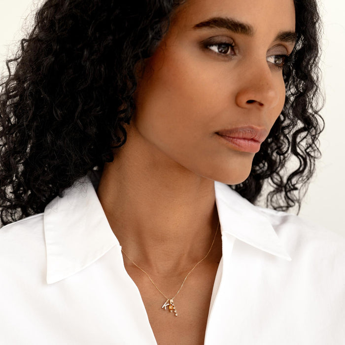 Close-up of woman wearing Diamond Drop Pendant 14k Gold with four diamonds on a delicate gold chain and white blouse