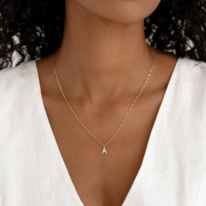 Close-up of woman wearing Diamond Initial Pendant 14k Gold - A on a delicate gold chain with white top background