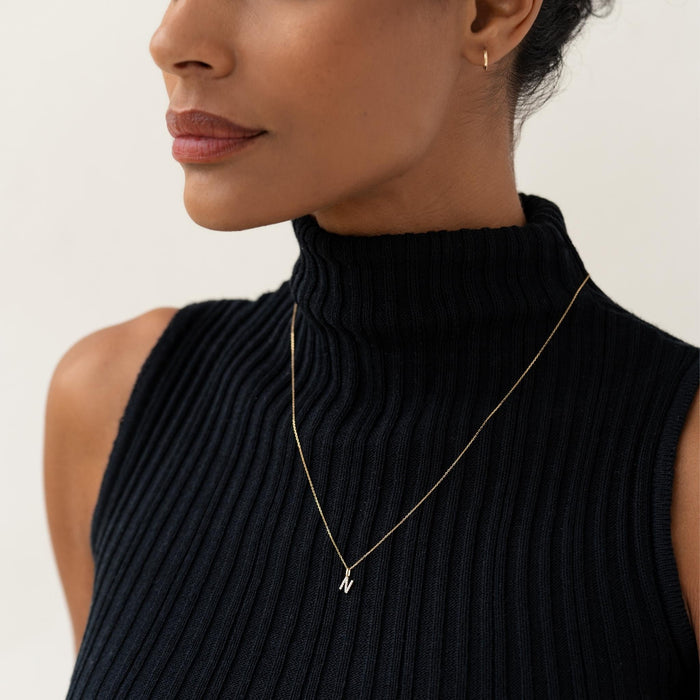 Close-up of a woman wearing Diamond Initial Pendant 14k Gold - N necklace with black ribbed sleeveless turtleneck