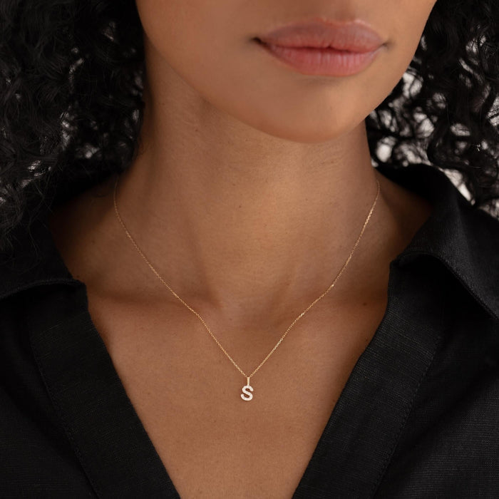 Close-up of woman wearing Diamond Initial Pendant 14k Gold - S on a delicate gold chain with a black top
