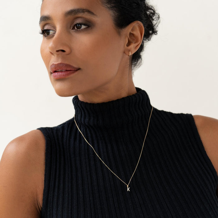 Close-up of a woman wearing Diamond Initial Pendant 14k Gold - S on a delicate chain with a black sleeveless top