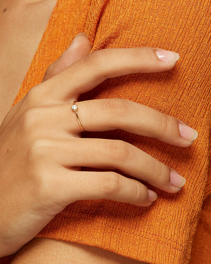 Lab grown bezel-set diamond ring on yellow gold band on model’s hand