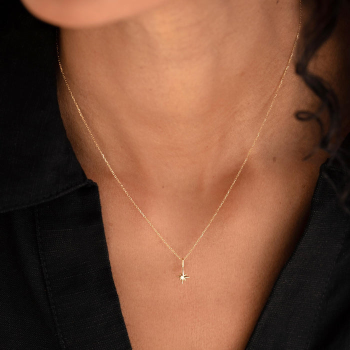 Close-up of a woman wearing the Diamond Star Charm 14k Gold pendant on a delicate gold chain with a black top
