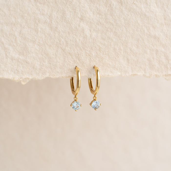 March Birthstone Drop Huggie Earrings - Aquamarine with pale blue gemstones set in gold vermeil on neutral background