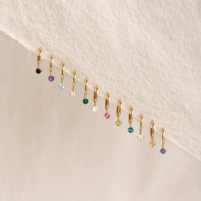 Row of gold vermeil huggie earrings with various birthstone colors including May Birthstone Drop Huggie Earrings - Green Chalcedony